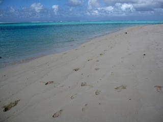Footprints left on a stretch of beautiful white sand beach with clear waters in a tropical island