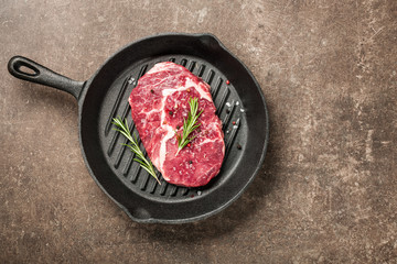 Fresh ribeye steak and spices on a pan
