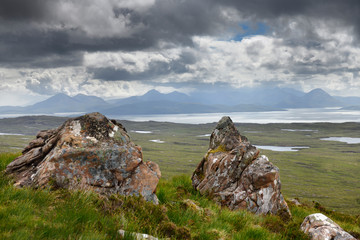 Lichen encrusted rocks overlooking the Inner Sound to Scalpay Island and the Cuillin Hills mountains Isle of Skye Scottish Highlands Scotland