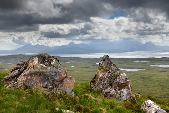 Lichen encrusted rocks overlooking the Inner Sound to Scalpay Island and the Cuillin Hills mountains Isle of Skye Scottish Highlands Scotland