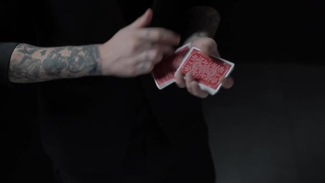 Young talented magician shows magic playing card trick. Close-up. 4K