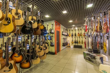 Foto op Plexiglas Muziekwinkel Een rij verschillende elektrische gitaren die in een moderne muziekwinkel hangen