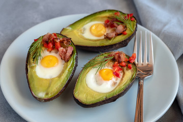 Quail eggs baked in avocado with bacon, red paprika and dill.