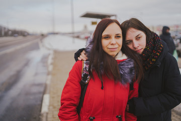 Two girls waiting for the bus at the bus station. Close up. The girls stand on the street