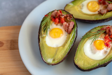 Quail eggs baked in avocado with bacon, red paprika and dill.