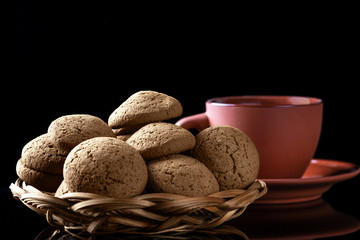 Oatmeal cookies and a cup of coffee on a black table.