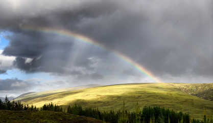 Fototapeta na wymiar Double rainbow and dark clouds on An Liathanach mountain at Loch a Chroisg near Badavanich Scottish Highlands Scotland UK