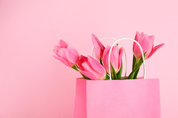 Beautiful bouquet of tender pink tulips in blank paper shopping bag. International Women's day, mother's day greeting concept. Copy space, close up, top view, flat lay.