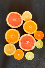 Fresh citrus fruits pieces sliced on black bacgkround, backdrop, orange, lemon, lime