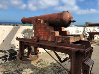 Side view of a cannon at Fort Charlotte with the Nassau harbor in the distance.