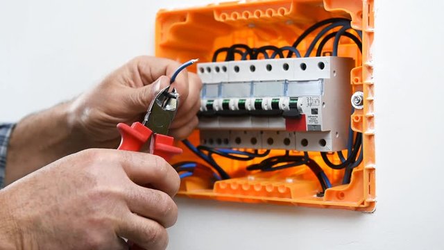 Video of the hands of the electrician technician cutting the electric cables in an electrical panel of a residential installation. Construction industry.