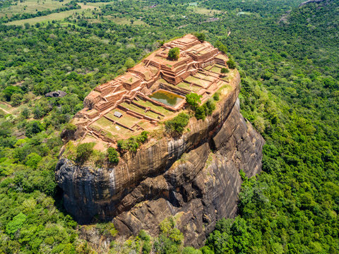 Aerial view from above of Sigiriya or the Lion Rock, an ancient fortress and a palace with gardens, pools, and terraces atop of granite rock in Dambulla, Sri Lanka. Surrounding jungles and landscape