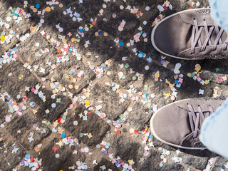 Pavement covered with colorful confetti and shoes