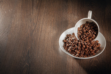  A white cup filled with natural roasted coffee beans.