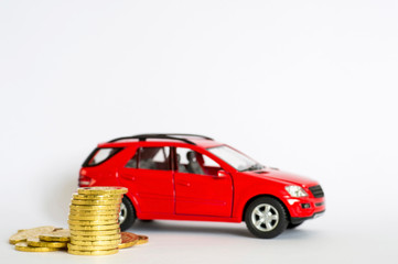A stack of shiny yellow coins on a background of red car on a light gray background.