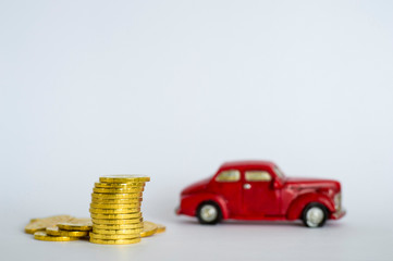 A stack of shiny yellow coins on a background of red retro car on a light gray background