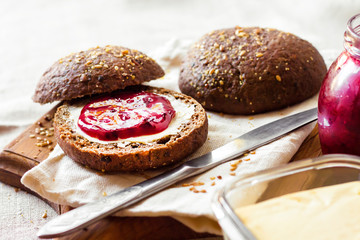 Homemade rye buns with linseeds, sesame and white poppy seeds served with butter and jam