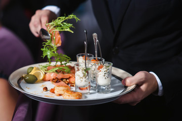 A waiter with a tray of snacks at a banquet or reception. Catering buffet at party