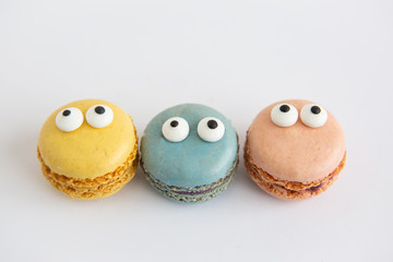 Three colorful macaron cookies with eyes