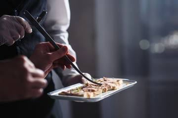 A waiter with a tray of snacks at a banquet or reception. Catering buffet at party