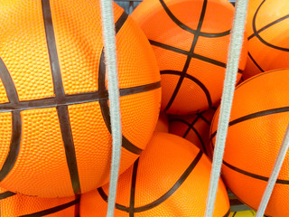 Obraz premium group of many new basketball orange balls with black lines at a sport shop ready to be sold behind some elastic white strings