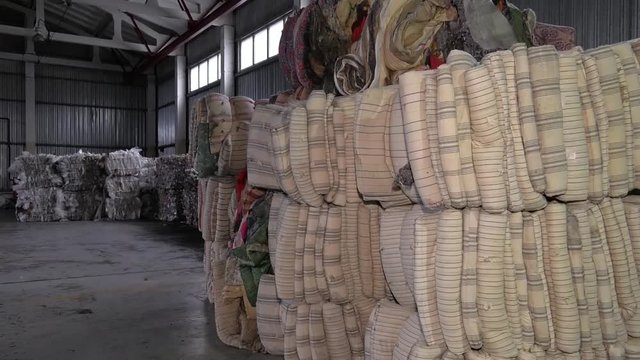 Sorting solid waste. Pressed bale. Recycling textile raw materials. Old, dirty, striped mattresses.