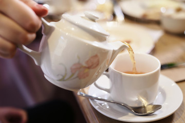 Morning tea breakfast. Kettle pouring boiling water into a cup during breakfast in morning sunlight