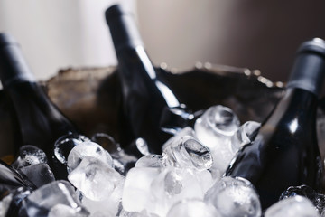 Closeup and selective focus of wine and champagne bottles chilling in a bucket full of ice.