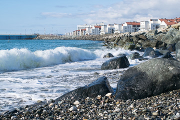 Beach with huge rocks and waves on the background of houses and water area on a Sunny day - 252491132