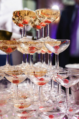 Champagne slide. Pyramid or fountain made of champagne glasses with cherry and steam from dry ice