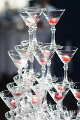 Champagne slide. Pyramid or fountain made of champagne glasses with cherry and steam from dry ice