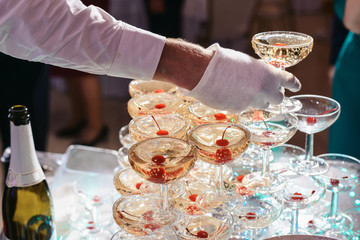 Champagne slide. Pyramid or fountain made of champagne glasses with cherry and steam from dry ice