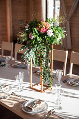 Bouquet with long branches of eucalyptus and flowers on the gold stand