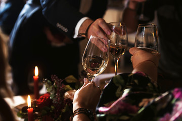 Close up shot of group of people clinking glasses with wine or champagne in front of bokeh background