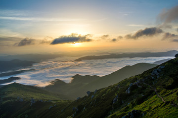 Fantastic view of mountain valley covered with low white puffy like snow clouds stretching to foggy...