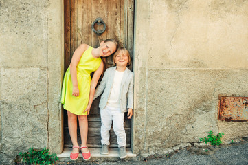 Obraz na płótnie Canvas Fashion portrait of adorable little boy and girl posing outdoors