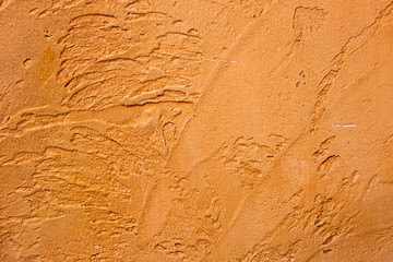 Close-up of colorful golden bronze plastered uneven stucco wall. Abstract texture, chaotic copy space background. Decorative grunge space.