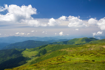 Fototapeta premium Green mountains panorama under blue sky on bright sunny day. Tourism and traveling concept, copy space background.