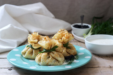 Bags of pancakes stuffed with herring, served with caviar, sour cream and dill on a wooden background. Rustic style.