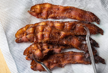 Cooked bacon fresh from the oven with tongs