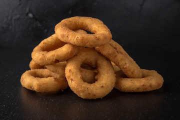 Rings of onions or squid in batter on black background. Snack to beer. Snack to beer. Fast food.