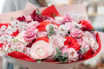 beautiful fresh cut bouquet of mixed flowers in woman hand. the work of the florist at a flower shop. Red and pink color