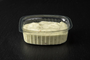 Sauce topping in plastic package for take away or food delivery isolated on a black background.
