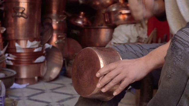 Chasing a traditional cooper dish with a hammer on craftsmans knee. Fes, Morocco, North Africa