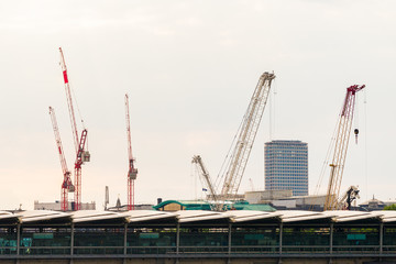 Construction cranes in London near Thames river. Construction and engineering concept. Cranes rebuilding old houses. Reconstruction of the of buildings.