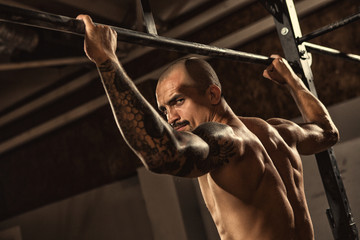 Athletic man performing pull ups at the gym