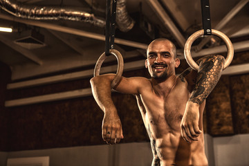 Male athlete working out on gymnastics rings at the crossfit gym