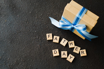 Happy Father's day greeting card with decorated gift box on dark background.