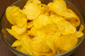potato chips with spices in a glass bowl on a wooden table