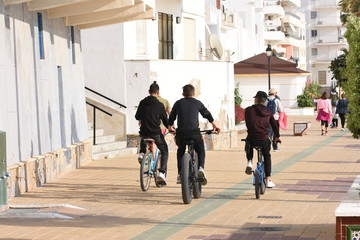 Niños en bicicleta en paseo marítimo de Andalucía bajo el sol